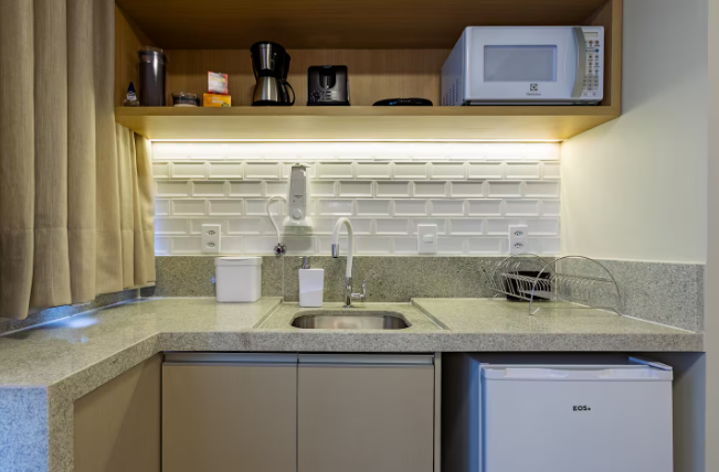 Cozinha compacta equipada com micro-ondas, cafeteira e frigobar