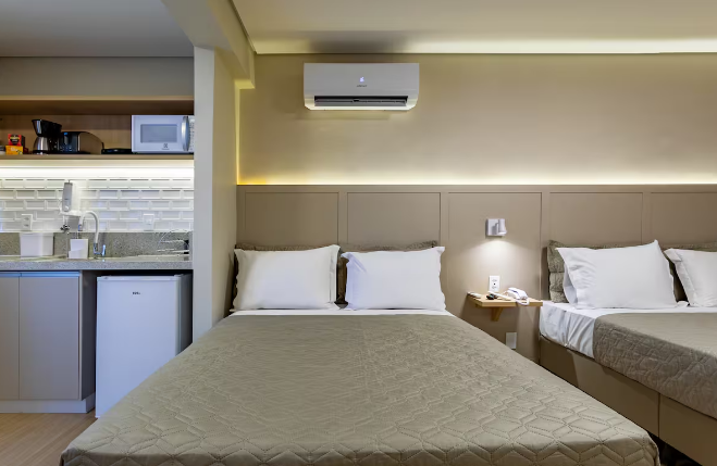 Quarto do flat com ar-condicionado e cozinha integrada